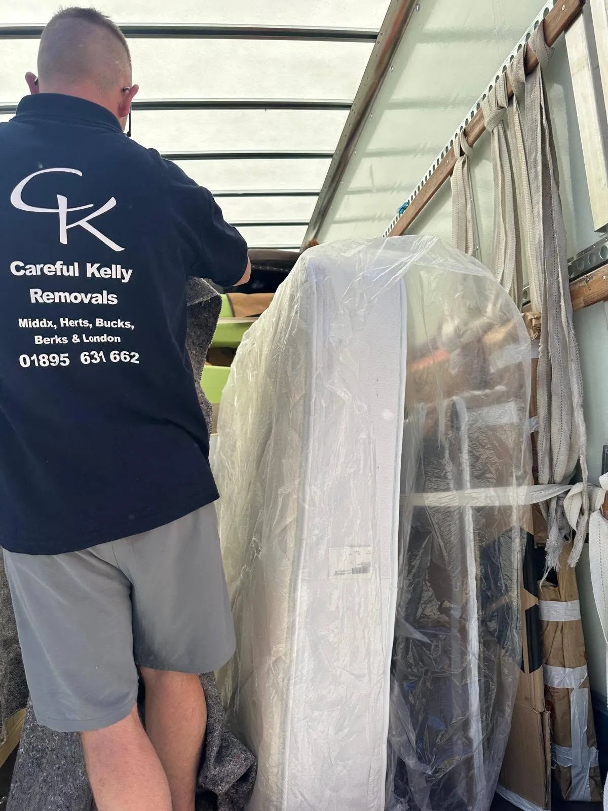 Careful Kelly Removals crew member wrapping and loading a mattress into a removal van